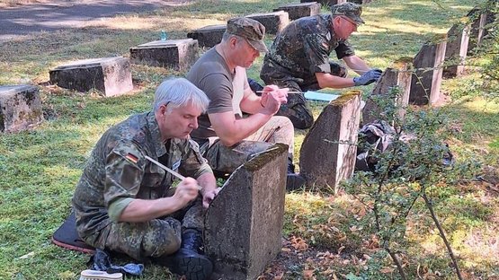 Menschen in Uniform reinigen Grabsteine