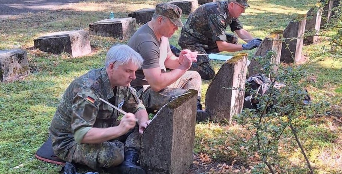 Menschen in Uniform reinigen Grabsteine